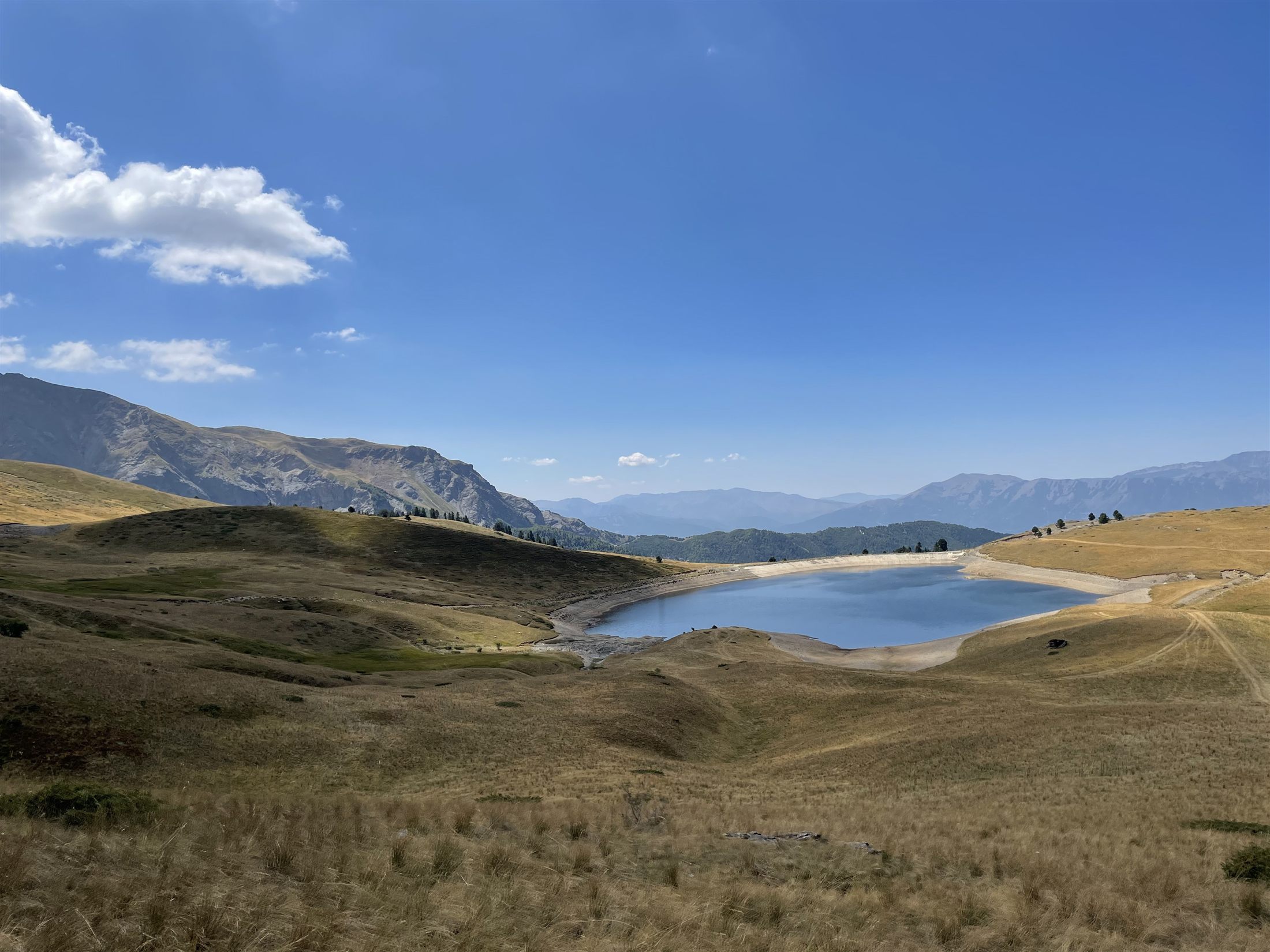 Lake Grama, a still mountain lake ringed by golden pasture