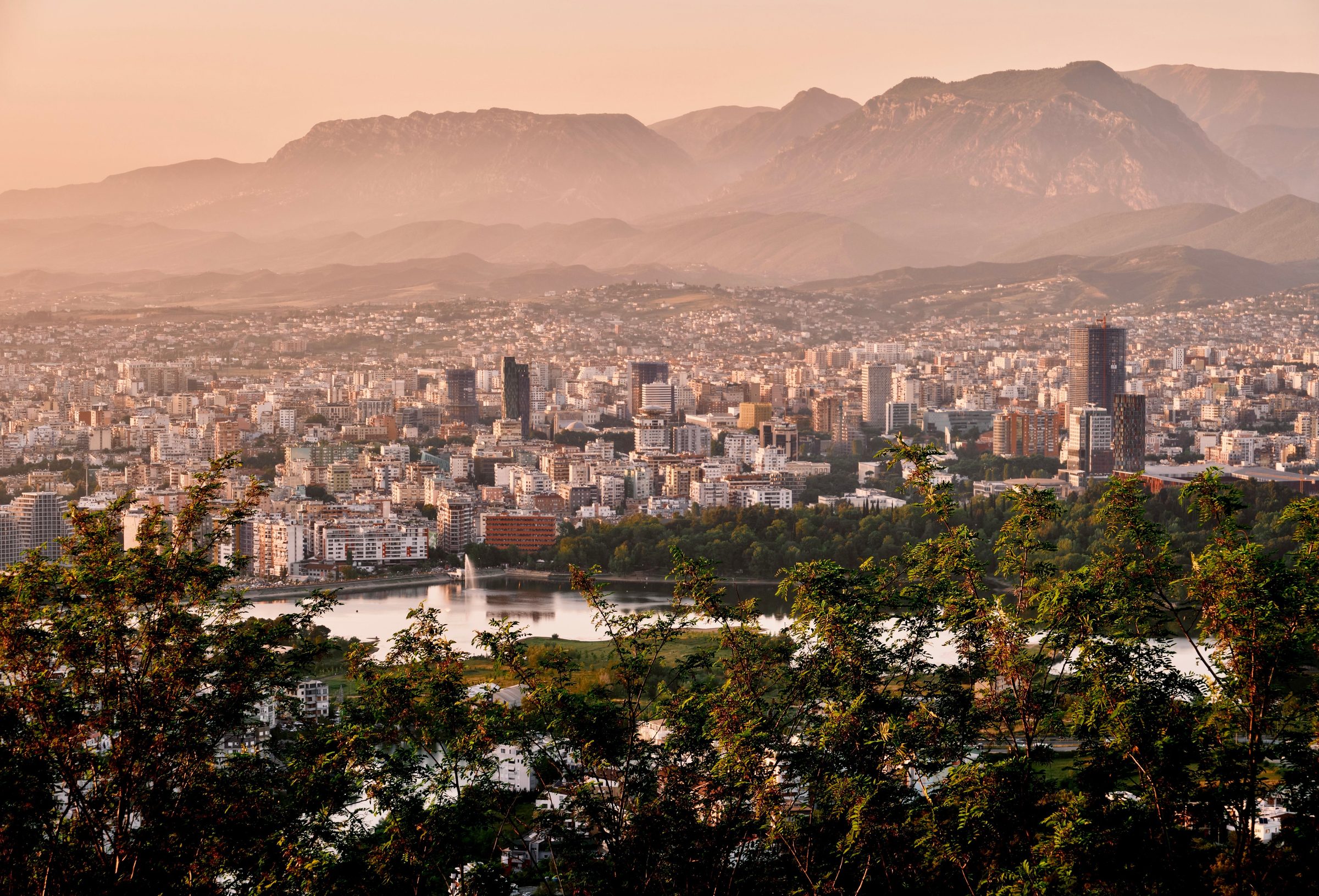 Tirana skyline and the artificial lake at sunset, mountains behind