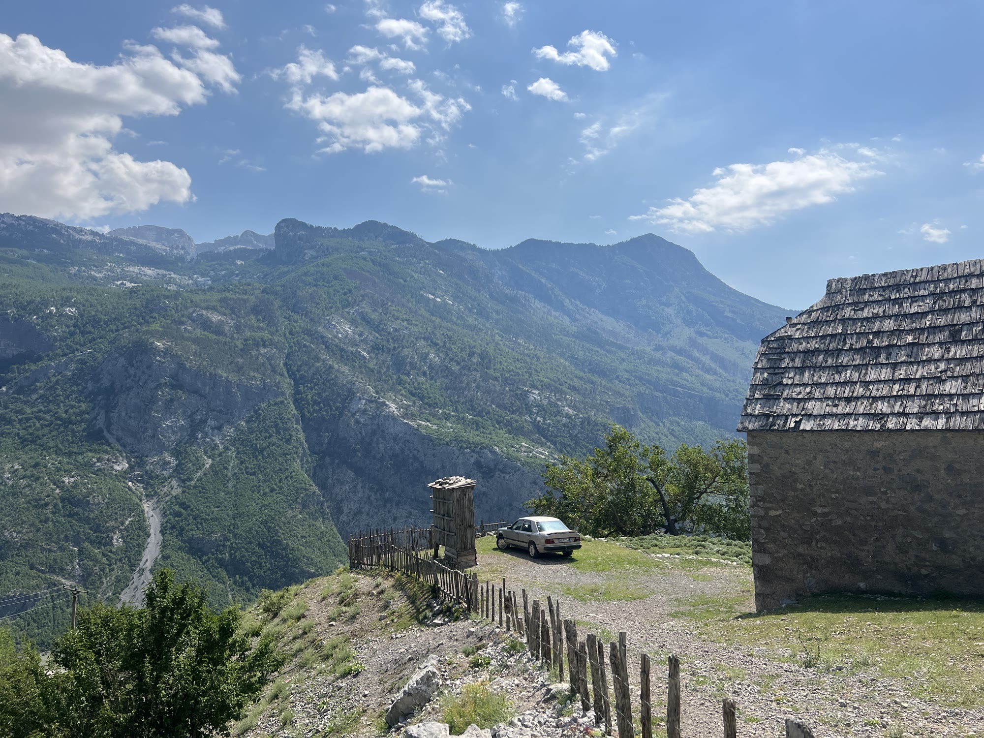 A traditional stone hut on a remote mountain ridge in Albania, sweeping valleys and peaks in the distance, no other visitors in sight